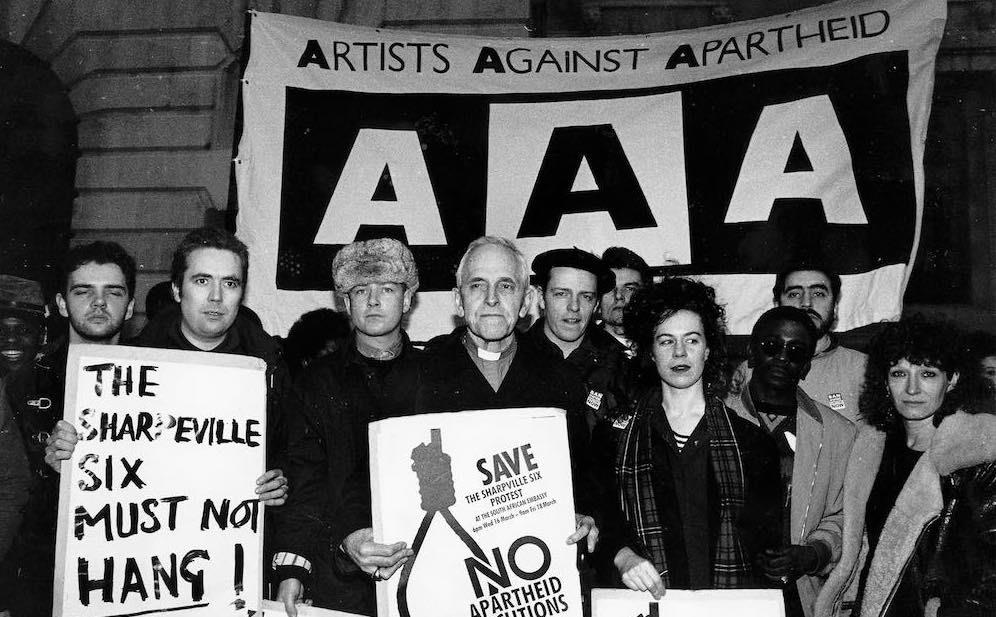 Artists Against Apartheid called for the release of the Sharpeville Six, 16 March 1988. In the photograph with Trevor Huddleston are (l to r) Jerry Dammers, Pat and Greg Kane from the pop duo Hue and Cry, and Suggs from the ska band Madness. The Sharpeville Six were sentenced to death in December 1985 because they were present at a protest where black collaborators were killed. In December 1987 the South African Appeal Court rejected their appeal for clemency. After an international campaign their sentence was commuted in July 1988.